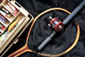 fishing rod laying in a fishing net next to a tackle box ready for weekend fishing