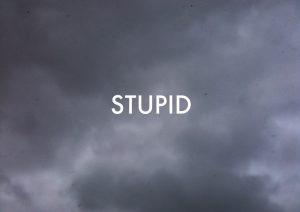 the word 'stupid' on dark clouds